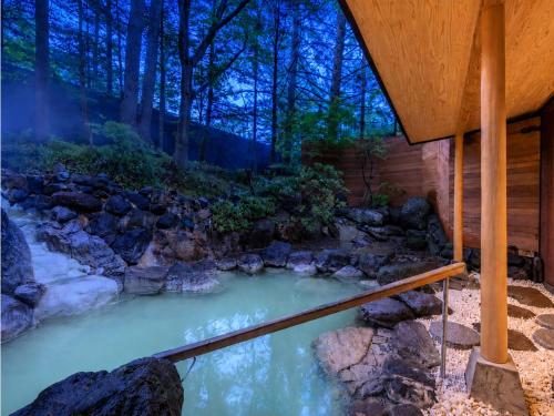 a pool of water next to a wooden house at UNWIND HOTEL & BAR Okunikko in Nikko