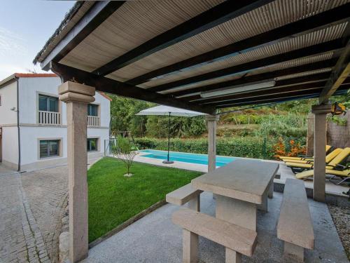 a wooden pergola with a picnic table and a pool at Charming villa in Cividade, 150 m² with private pool in Cividade
