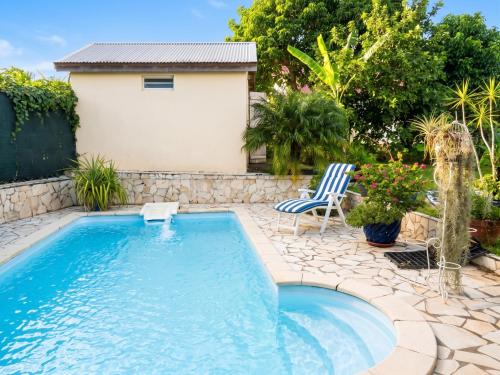 a swimming pool with a patio and a chair in a yard at Studio accueillant à Baie Mahault - 20 m² avec piscine privée in Baie-Mahault