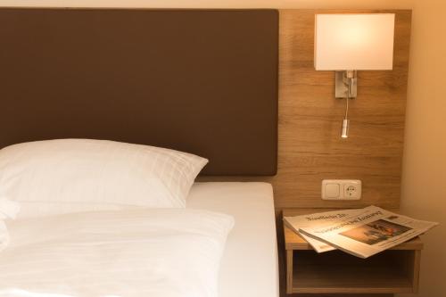 a bedroom with a bed and a newspaper on a night stand at Hotel Heldt in Bad Pyrmont