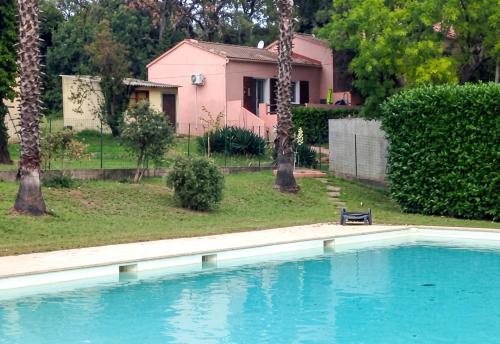 a swimming pool in front of a pink house at Maison charmante à San-Nicolao avec piscine partagée in San-Nicolao