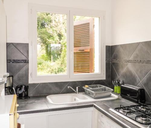 a kitchen with a sink and a window at Maison charmante à San-Nicolao avec piscine partagée in San-Nicolao