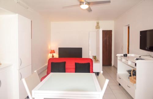 a living room with a white table and a red chair at Charmant studio avec vue sur mer au Moule, 20 m² + terrasse in Le Moule