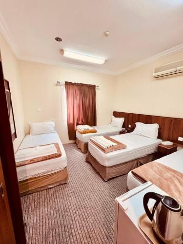 a hotel room with two beds and a kitchen at فندق جوهرة ذاخر رويال توصيل مجاني للحرم - Jewel Thakher Royal Hotel Free Shuttle to Haram in Mecca
