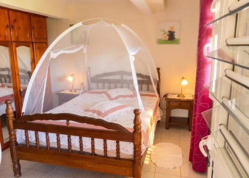 a bed with a canopy in a room at Appartement douillet avec vue sur les montagnes au Vauclin in Le Vauclin