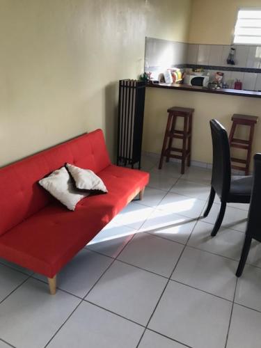 a red couch in a living room with a kitchen at Appartement avec vue sur la mer à Le Marin, Climatisé, 80 m² in Le Marin