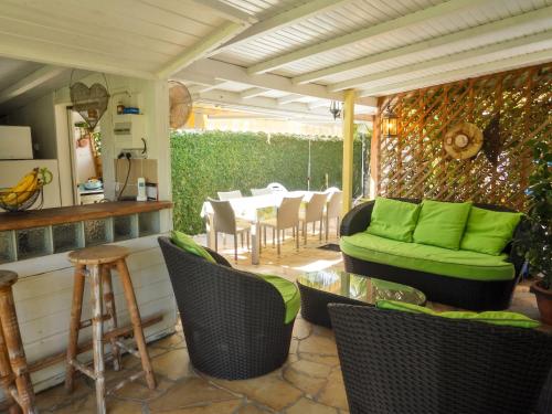 a patio with green cushioned chairs and a table at Chalet confortable au Vauclin avec piscine privée in Le Vauclin