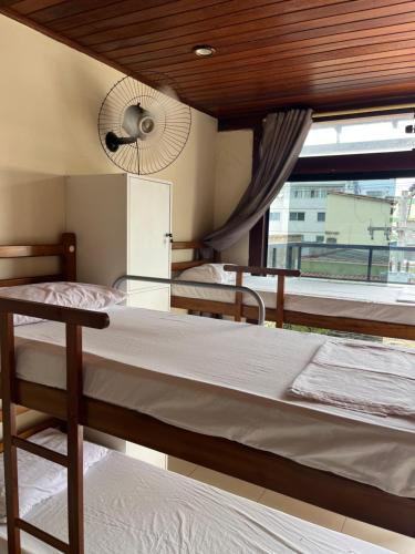 a bedroom with two beds and a window with a fan at Preservar hostel in Cabo Frio