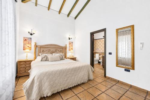 a white bedroom with a bed and a mirror at CERCADO DEL MEDIO, CHALET con PISCINA PRIVADA in Adeje