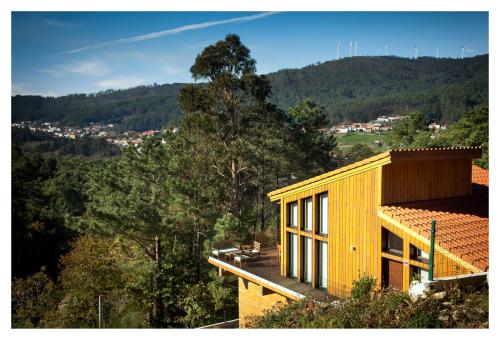 a yellow house on top of a hill with trees at Elegant Villa in Outes with Pool in Serantes