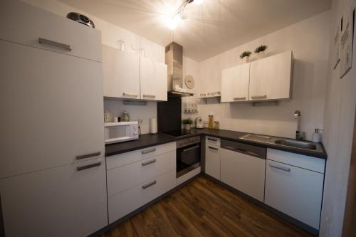 Una pequeña cocina con gabinetes blancos y un fregadero. en Ferienwohnung Prantner, en Rauris