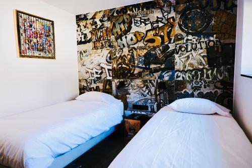 a room with two beds and a wall covered in graffiti at Cit'Art in Namur