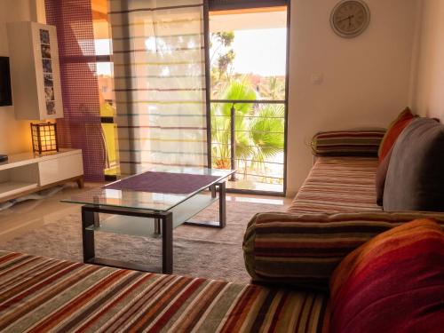 a living room with a couch and a glass table at Charming Apartment in Imi Ouaddar in Agadir nʼ Aït Sa