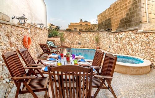 a patio with a table and chairs next to a swimming pool at Exceptional villa in In-Nadur with private pool. in Nadur