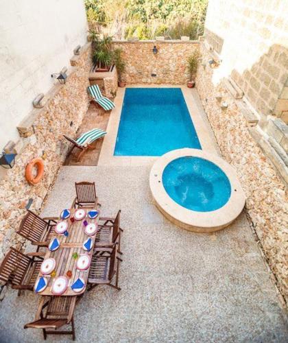 an outdoor swimming pool with chairs and a table and a swimming pool at Exceptional villa in In-Nadur with private pool. in Nadur