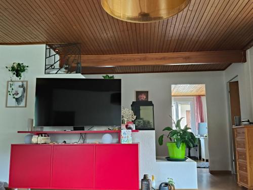 a living room with a red cabinet and a flat screen tv at Grosses Doppelzimmer in Privathaus in Flums