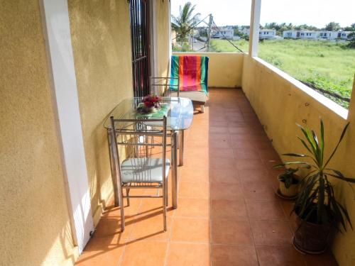 a balcony with two chairs and a glass table at Charming Apartment in Pamplemousses, 30 m² with Garden View in Pamplemousses Village