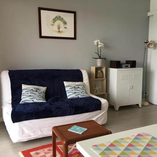 a living room with a couch with a blue blanket at Appartement cosy avec piscine partagée - Guérande - 30 m² in Guérande