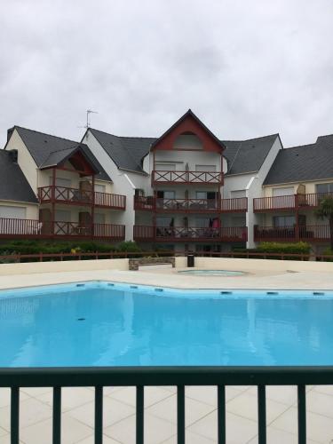a large apartment building with a pool in front of it at Appartement cosy avec piscine partagée - Guérande - 30 m² in Guérande
