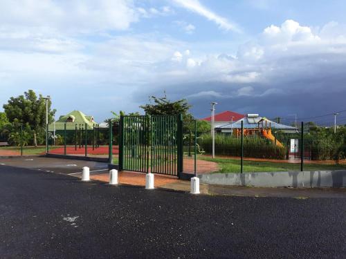 a playground with a gate on the side of a street at Studio accueillant à Baie Mahault, 22 m², piscine partagée. in Baie-Mahault