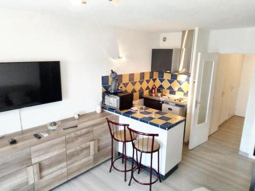 a kitchen with a counter and two bar stools at Studio charmant à Fréjus avec piscine commune - 30 m² in Fréjus