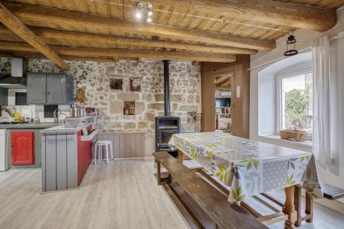a kitchen with a table and a stone wall at Maison charmante à Valprivas avec jardin privé. in Valprivas
