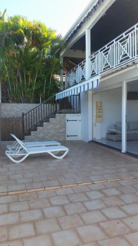 a patio with a bed and a chair in front of a house at Appartement confortable avec terrasse à Petit-Canal - 50 m² in Petit-Canal