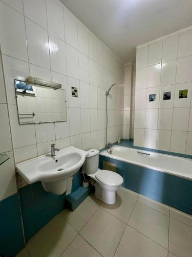 a bathroom with a sink and a toilet and a tub at Immeuble Mohamet Mbacké TAÏF in Dakar