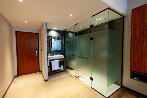 a bathroom with a glass shower and a sink at Le Louvre Hotel & Spa in Antananarivo