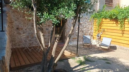 two chairs and a tree on a wooden deck at Le cabanon in Flayosc