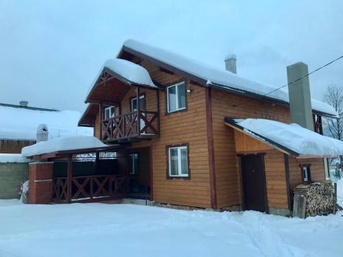 a log cabin with snow on the roof at Котедж Amber in Mykulychyn
