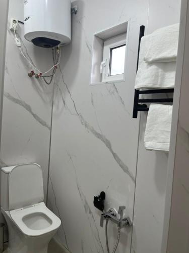 a white bathroom with a toilet and a window at Алаша in Qotanqaraghay