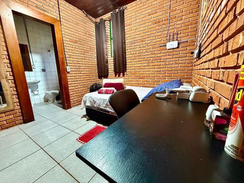 a room with a table and a brick wall at Quarto com Banheiro Privado no Centro de Botucatu in Botucatu
