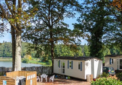 a tiny house parked next to a lake at Bungalow charmant à Rochechouart avec vue sur lac in Rochechouart