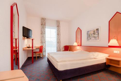 ein Hotelzimmer mit einem Bett und einem TV in der Unterkunft Hotel Montana Lauenau in Lauenau