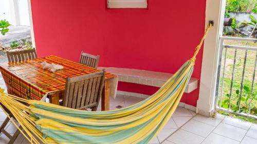 a hammock sitting next to a table and a table and chair at Maison confortable Le Moule Jacuzzi in Le Moule