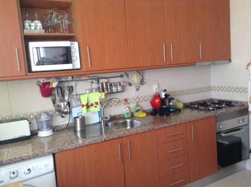 a small kitchen with a sink and a microwave at Comfortable apartment with lake view in Vila Real - 75m² in Vila Real de Santo António
