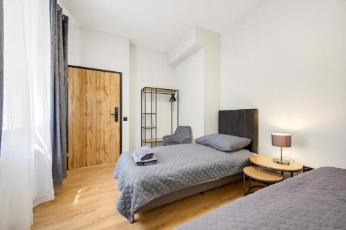 a bedroom with two beds and a wooden floor at Centrum Grand Apartments in Rybnik