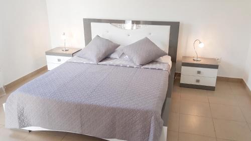 a bedroom with a white bed with two night stands at Villa enchanteresse à Saint-Benoît avec piscine privée in Saint-Benoît