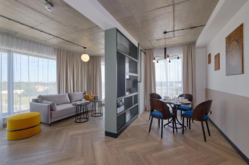 a living room with a couch and a table and chairs at Arche Hotel Wrocław Airport in Wrocław