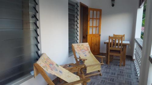 a porch with two rocking chairs and a table at Comfortable apartment in Baie Sainte Anne 56 m² with sea view in Baie Sainte Anne