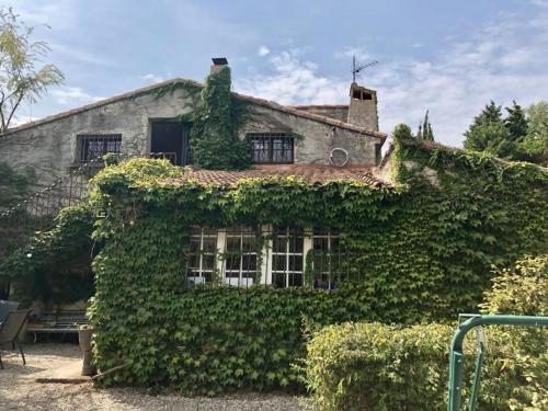 an ivy covered house with a window at Villa avec piscine à Saze in Saze