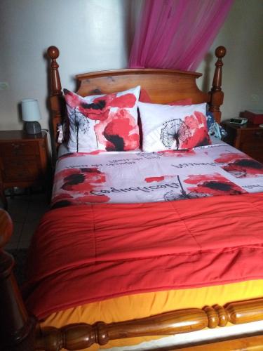 a bed with a red blanket and pillows on it at Appartement panoramique Bouillante in Bouillante