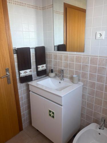 a bathroom with a sink and a toilet and a mirror at Casa da Maré in Calheta
