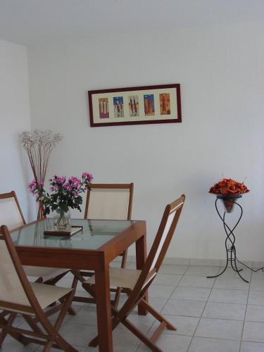 a dining room with a table and chairs and flowers at Appartement avec terrasse à Fréjus, 70 m², piscine partagée in Fréjus