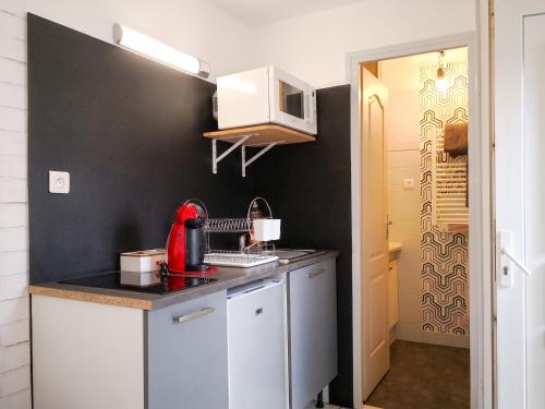 a small kitchen with a red appliance on a counter at Studio cosy à Montargis - 13 m² - Parking inclus in Montargis