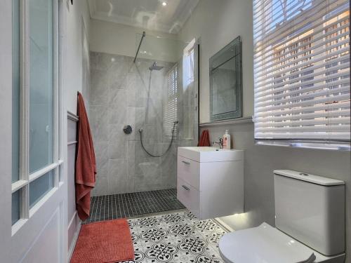 a bathroom with a shower and a toilet and a sink at GreenMarket Apartment in Knysna