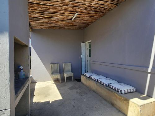 a porch with two chairs and a bench in a building at GreenMarket Apartment in Knysna