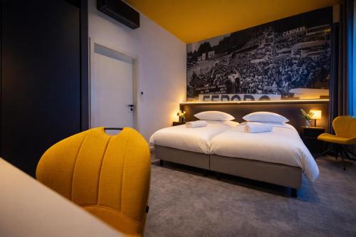 a hotel room with two beds and a yellow chair at La Reine Hôtel & Restaurant in Spa