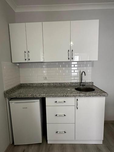 a white kitchen with a sink and white cabinets at Hamsiköy Doruk Apart in Macka